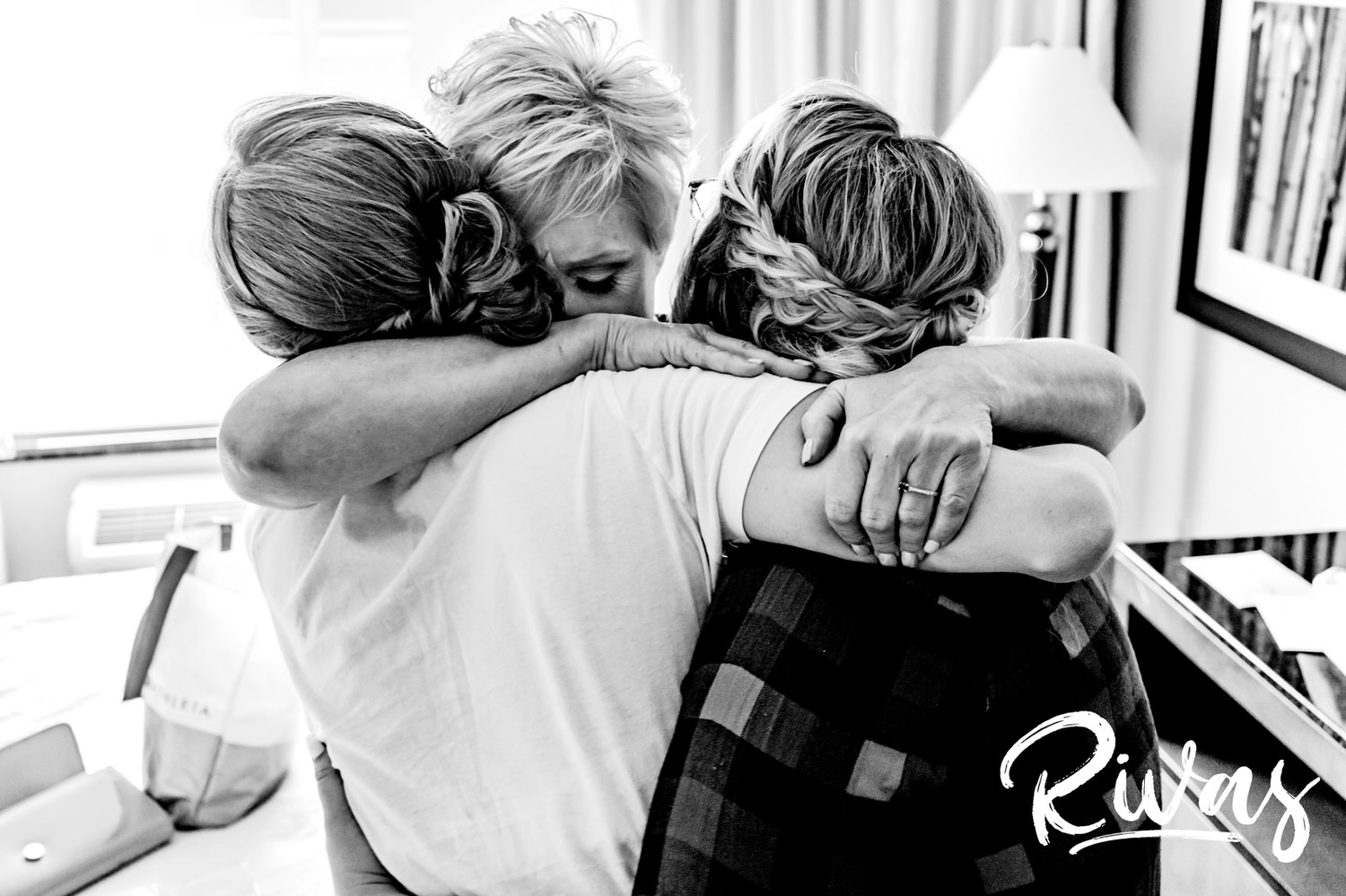 An emotional, black and white photo of a woman hugging two of her daughters on the morning of her Omaha, NE wedding. 