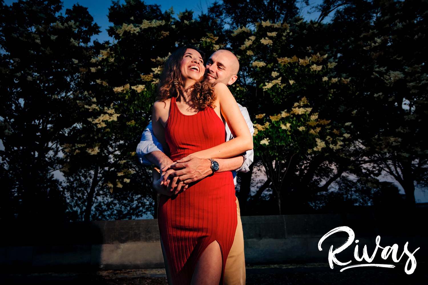 A fun, candid picture of a man holding a woman around the waist as they laugh together during their engagement session at Kansas City's Liberty Memorial. 