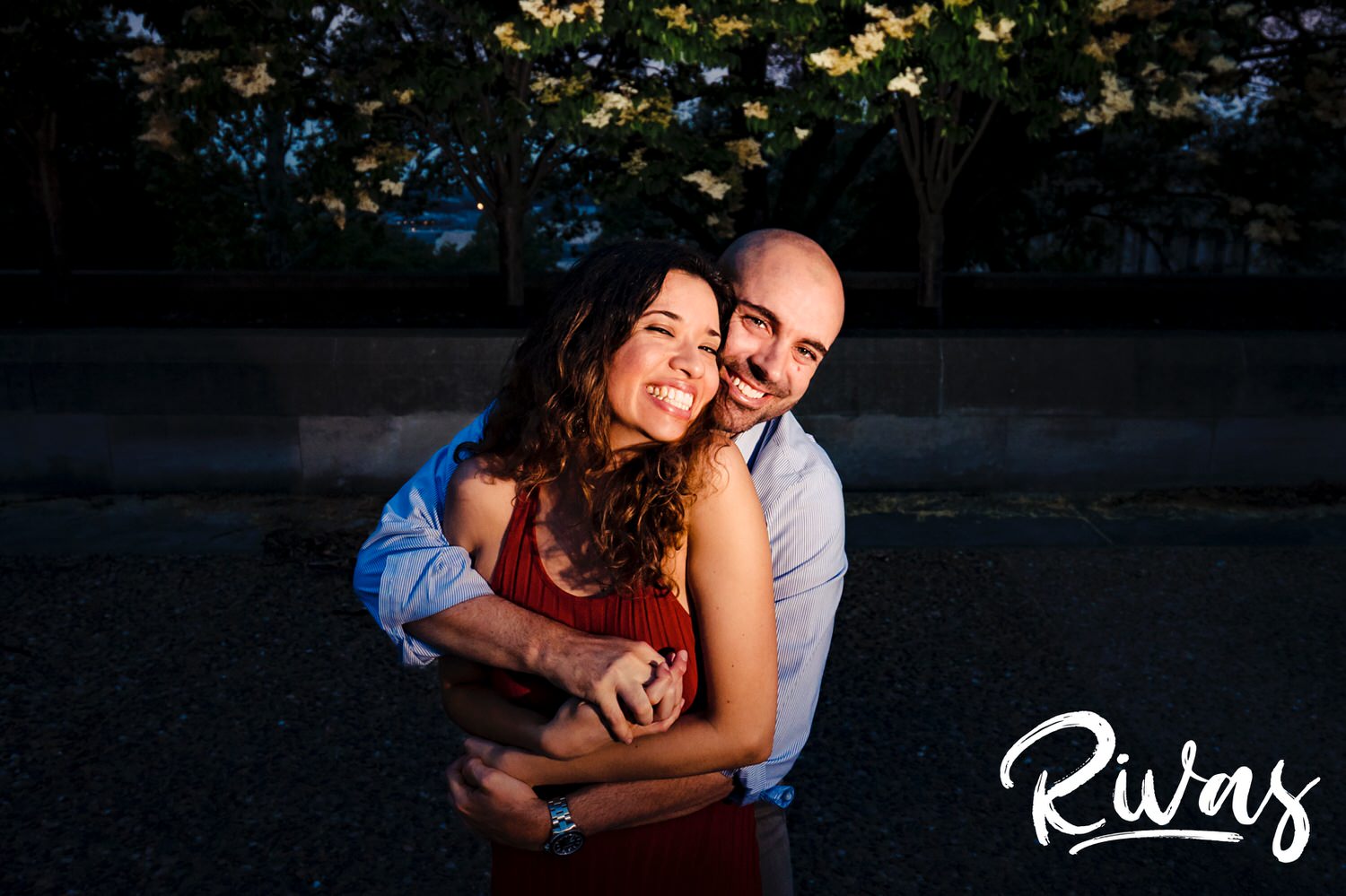 A fun, candid picture of a man holding a woman around the waist as they laugh together during their engagement session at Kansas City's Liberty Memorial. 