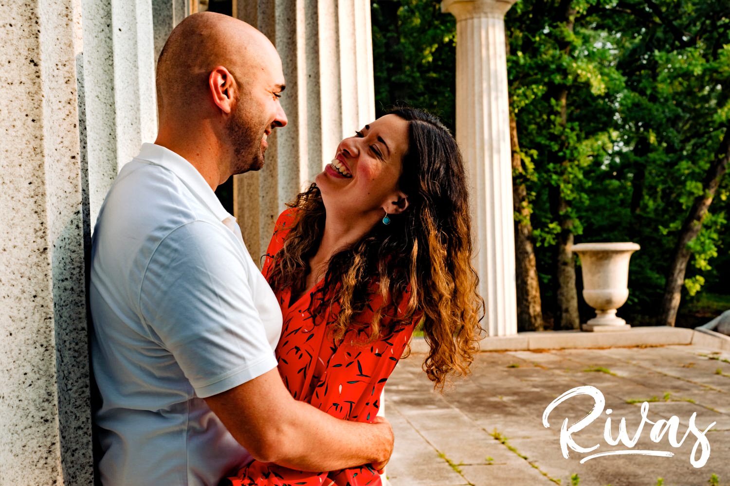 A colorful, candid picture of a man holding on to a woman's waist as she smiles and laughs at him during their Kansas City engagement session. 