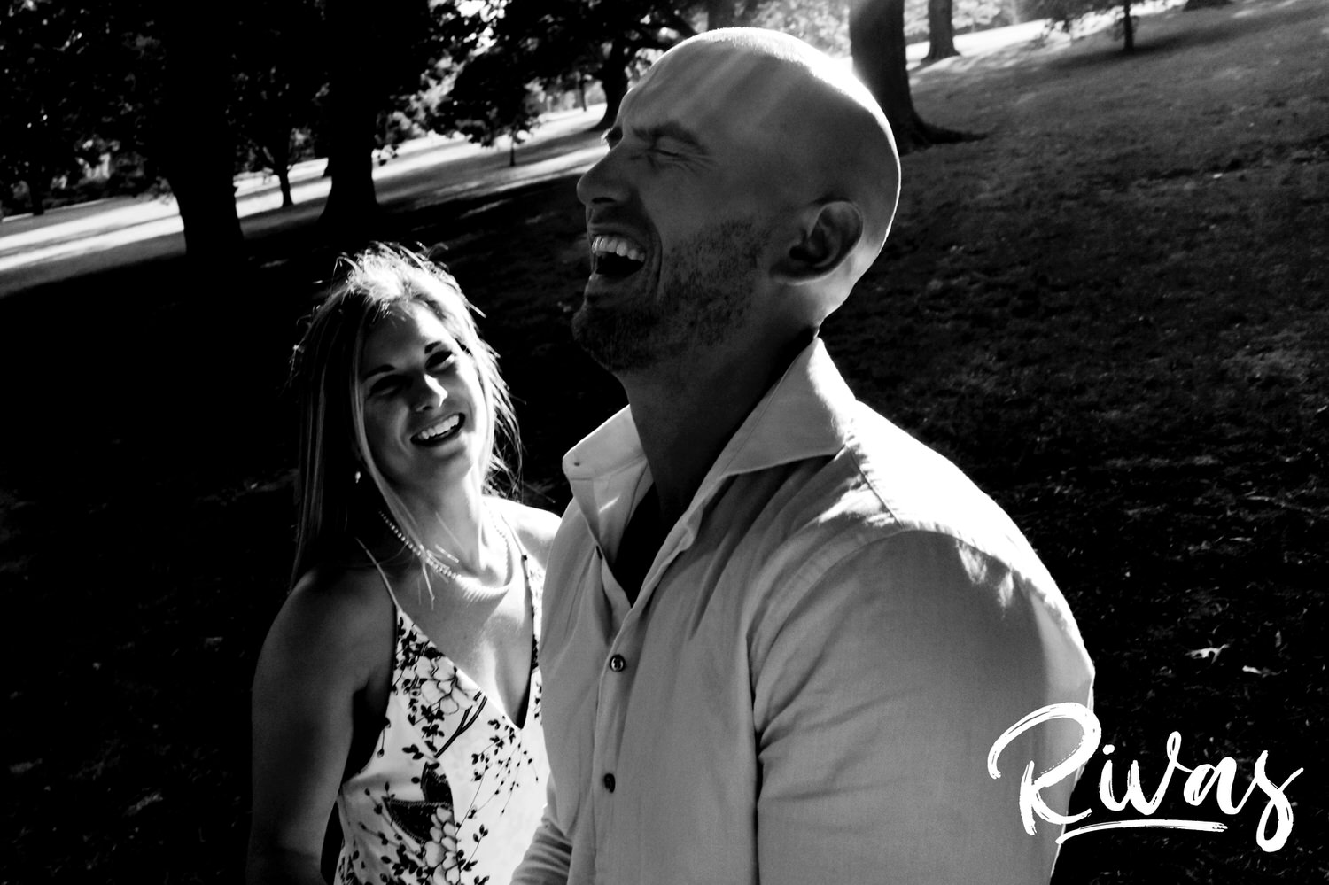 A candid black and white picture of an engaged couple laughing hysterically during their engagement session at Kansas City's Loose Park. 
