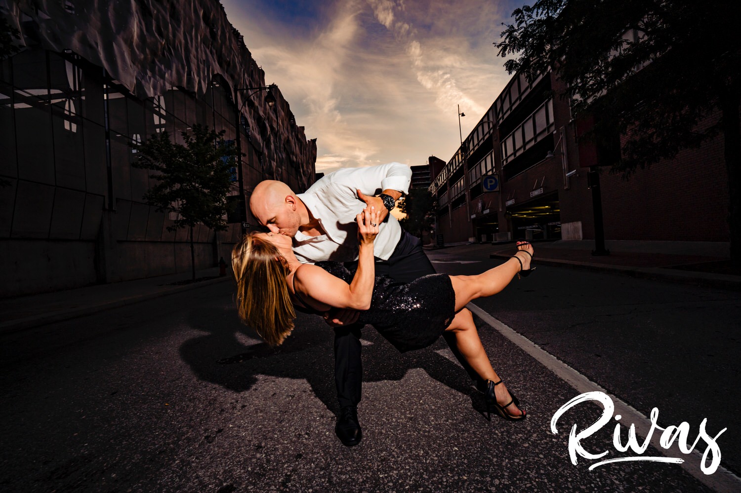 A bright, candid picture of an engaged couple dipping and sharing a kiss in the middle of a Kansas City street during their engagement session. 
