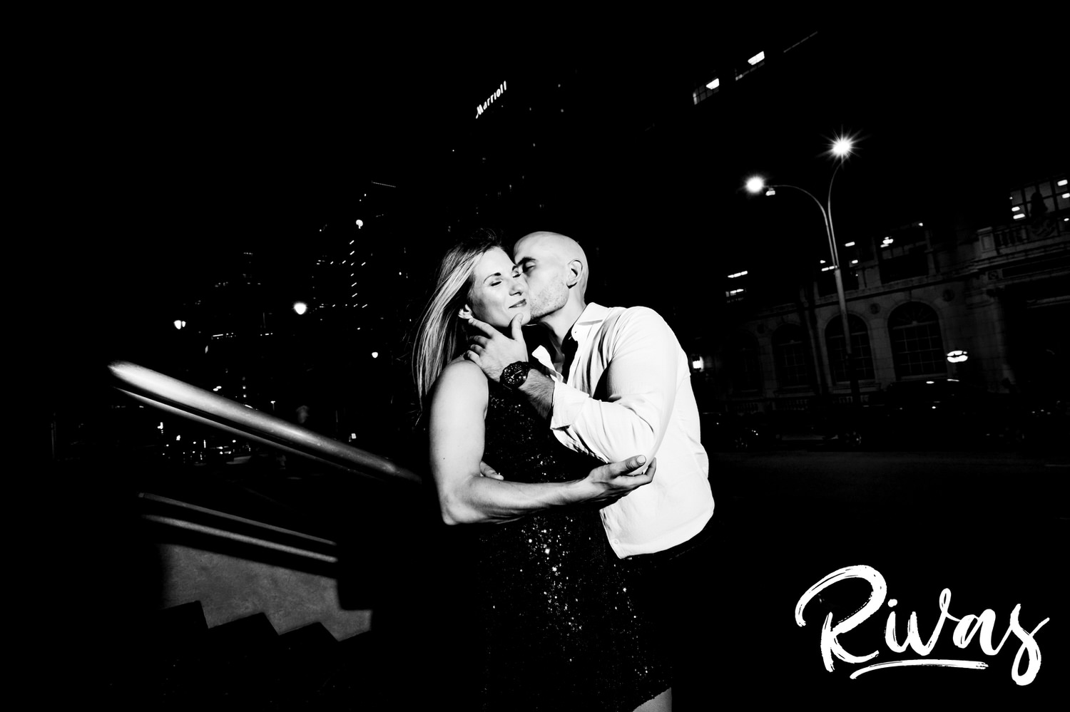 A romantic, black and white picture of a man softly kissing a woman's cheek during their engagement session in downtown Kansas City. 