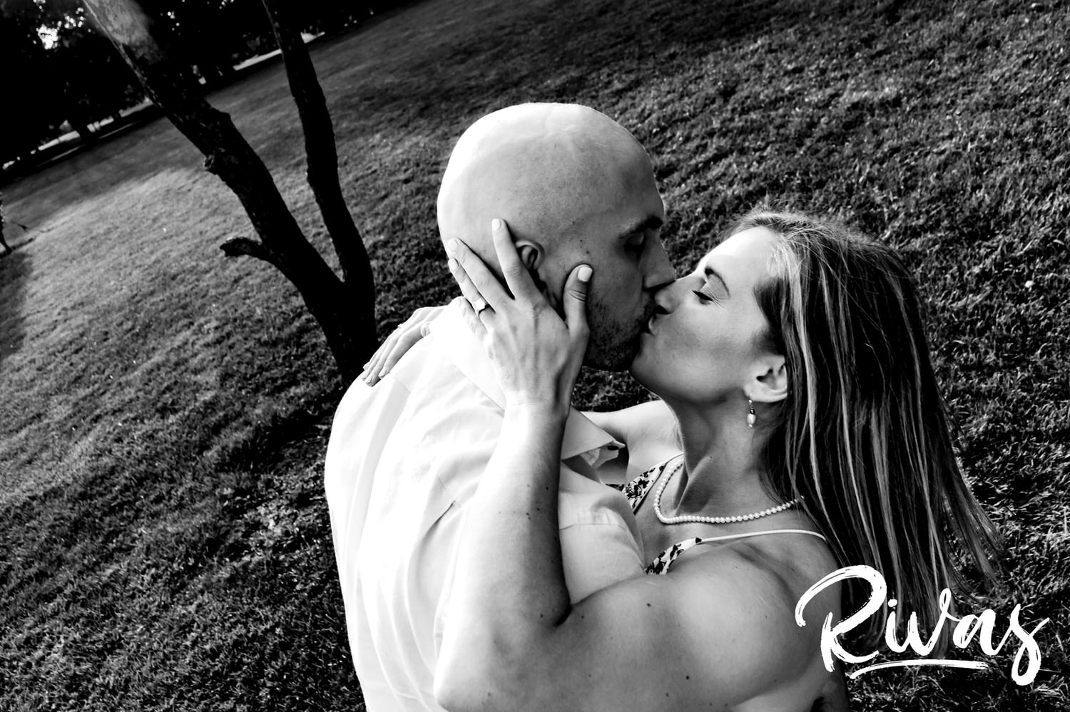 A candid black and white picture of an engaged couple sharing a kiss during their engagement session at Loose Park in Kansas City. 