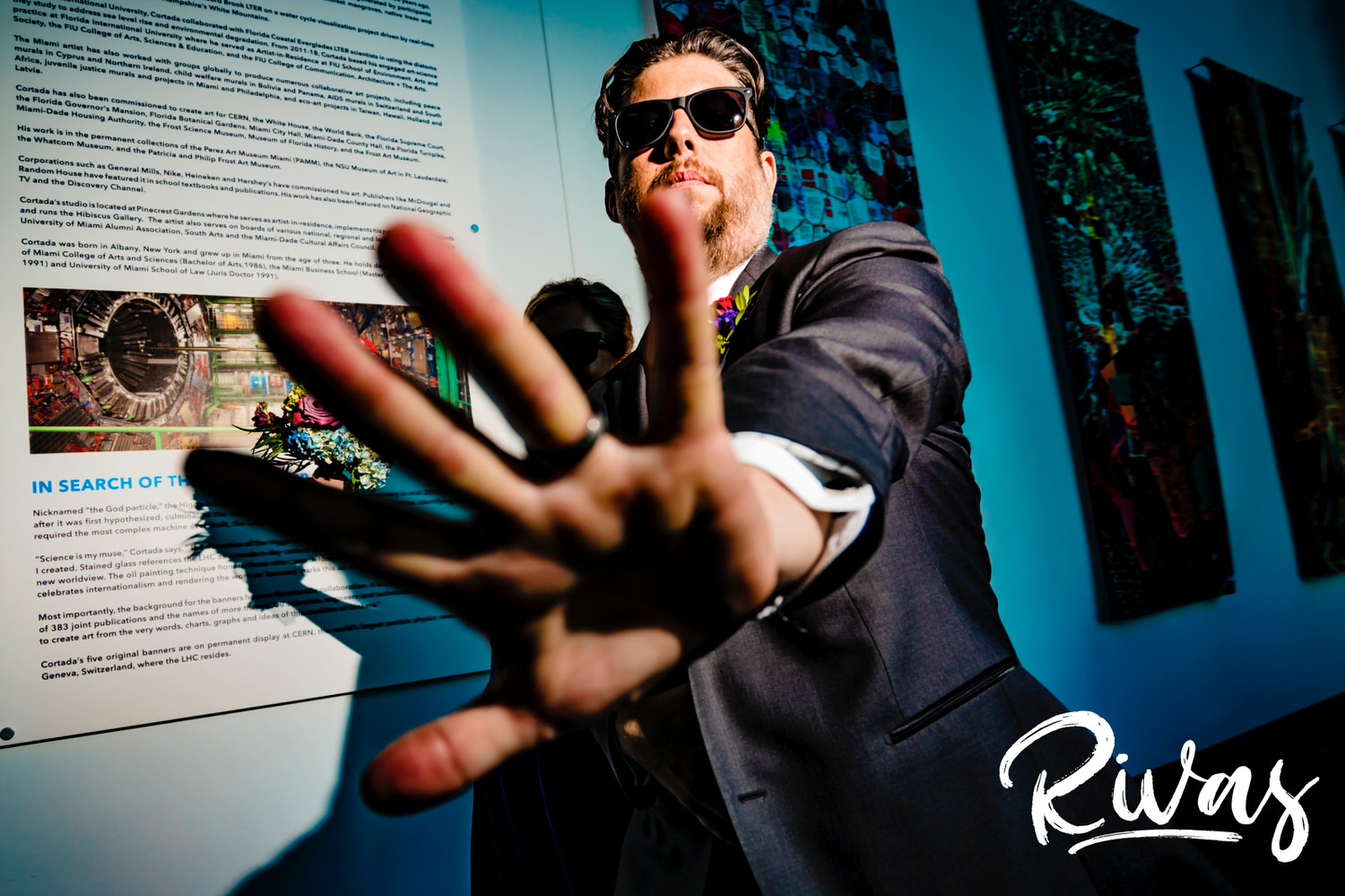 A candid picture of a groomsman holding his hand out in front of the camera as he enters a wedding reception at The Museum at Prairiefire. 