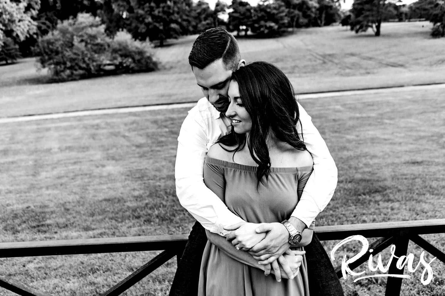 A black and white picture of an engaged couple wrapped up in each others' arms during their summer engagement session at Loose Park in Kansas City. 