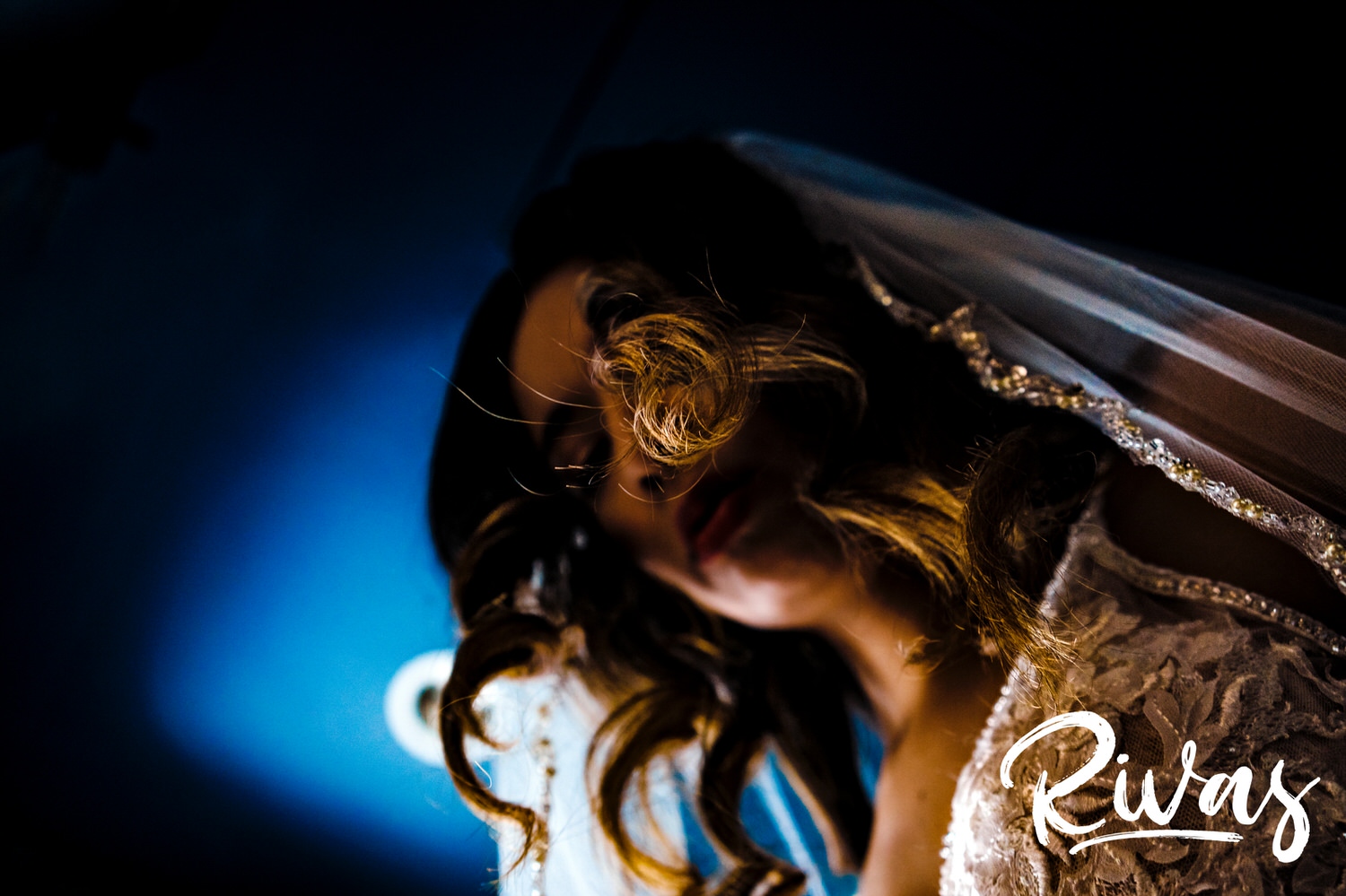 A vibrant, detailed picture taken from the ground looking up of a bride's curly hair, veil, and wedding gown. 