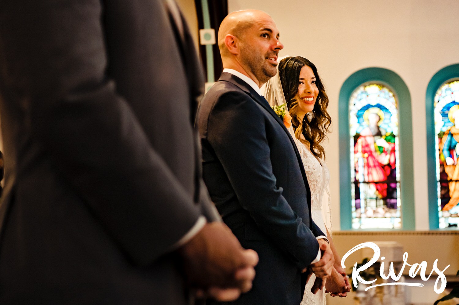A candid picture taken from the side of a bride and groom smiling at their officiate during their Kansas City wedding ceremony. 