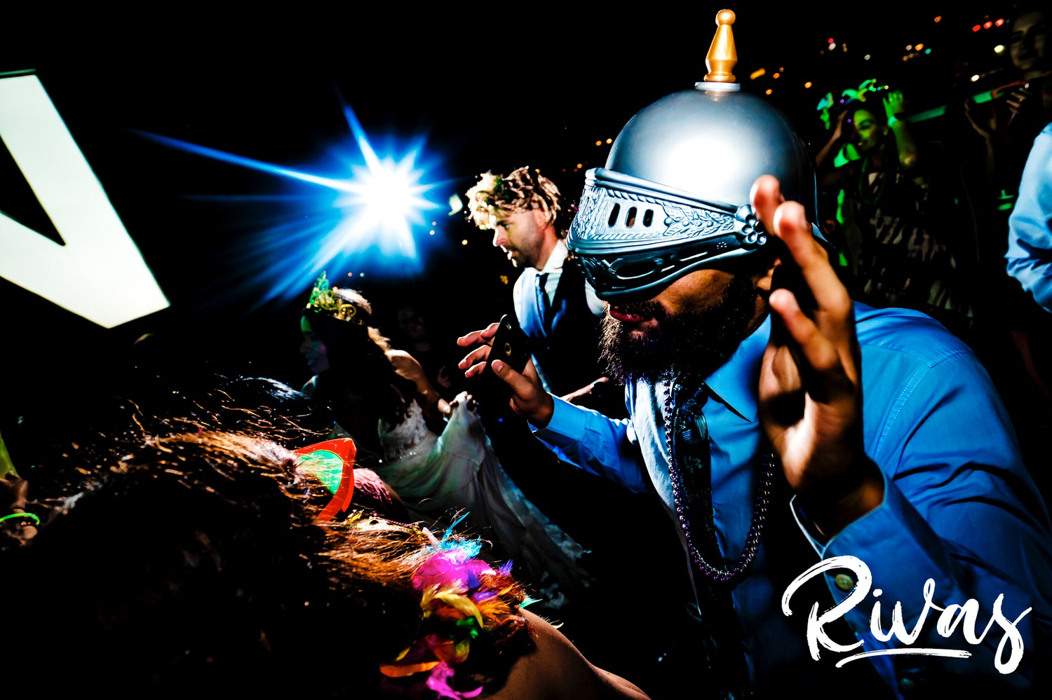 A candid picture of a man in a knight's mask dancing enthusiastically during a wedding reception in Kansas City. 