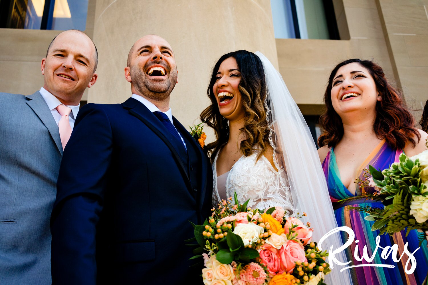 A tight, candid picture of a bride and groom laughing hysterically on their wedding day with their best man and maid of honor at The Nelson Atkins Museum of Art on the day of their Kansas City wedding. 