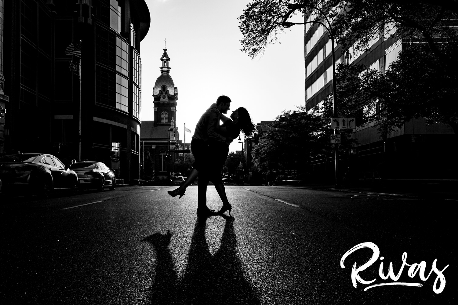 A dramatic, black and white picture of an engaged couple dancing in the middle of a city street during their fall engagement session downtown. 