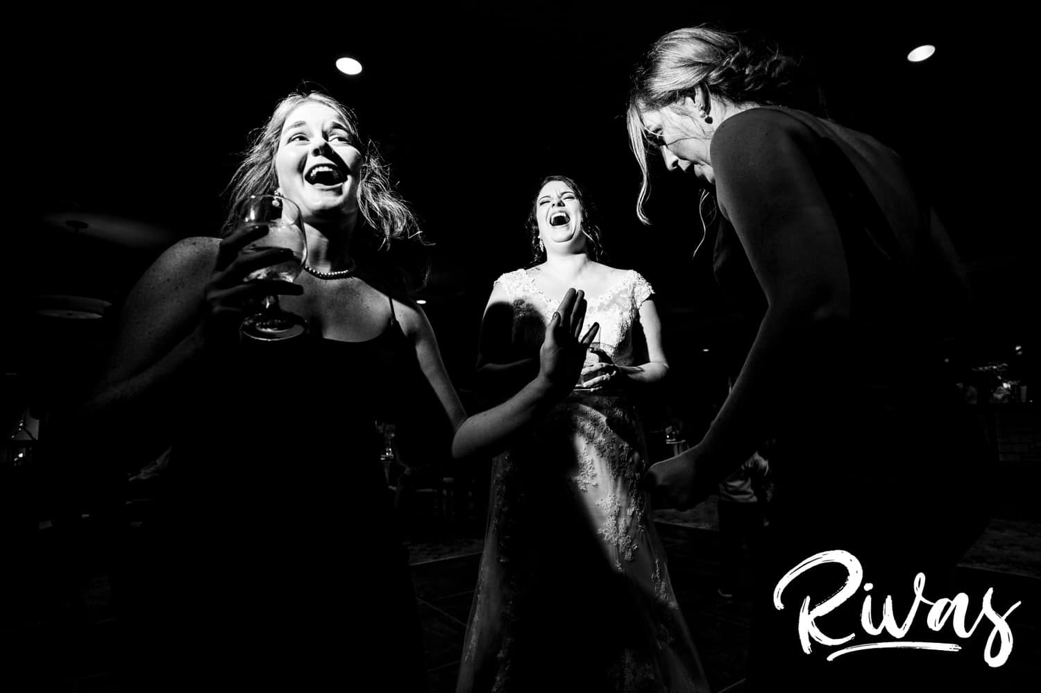 A candid black and white picture of a bride laughing and dancing with her bridesmaids during her summer wedding reception at Lawrence Country Club. 
