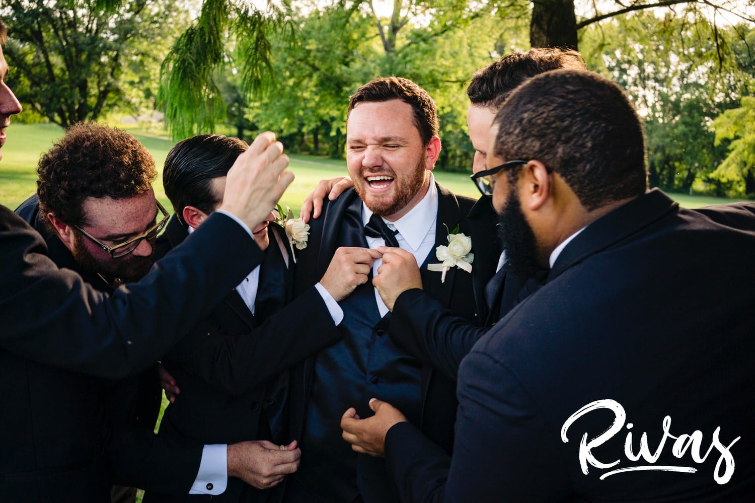 A candid picture of a groom and his groomsmen laughing hysterically during wedding party pictures at Lawrence Country Club on his summer wedding day. 