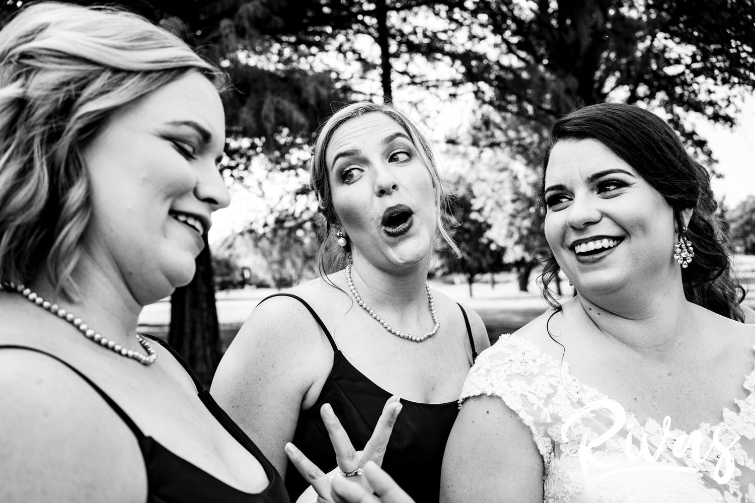 A candid black and white picture of a bride and her bridesmaids smiling and laughing together on a summer wedding day at Lawrence Country Club. 