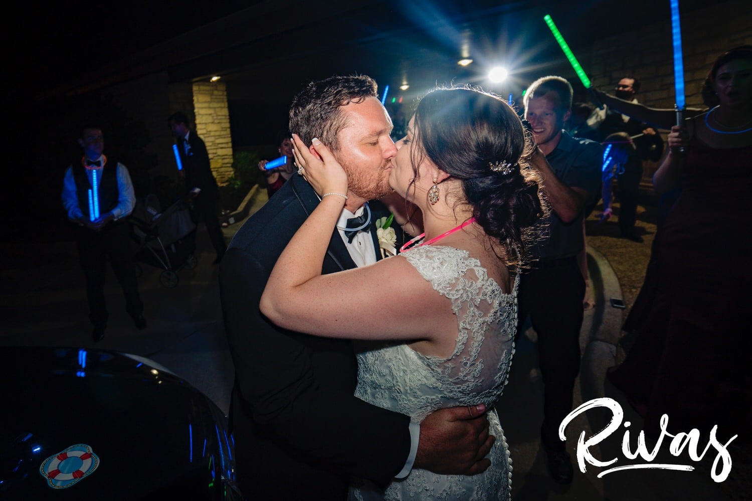 A candid picture of a bride and groom holding hands and running under an arc of light sabers after their summer wedding day at Lawrence Country Club. 