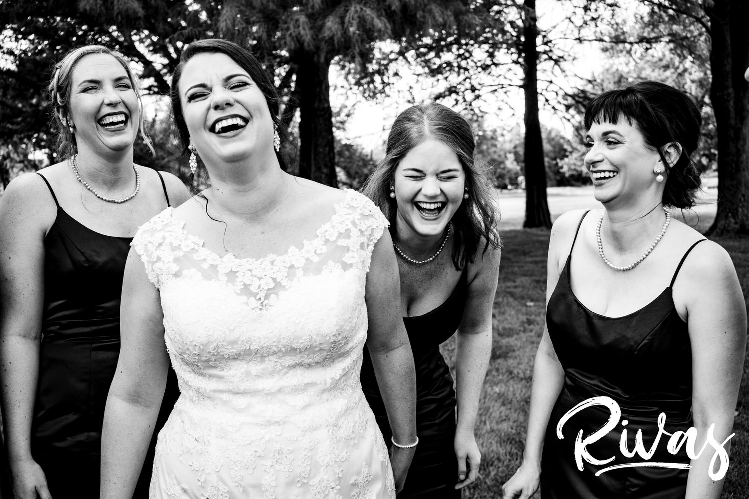 A candid black and white picture of a bride and her bridesmaids smiling and laughing together on a summer wedding day at Lawrence Country Club. 