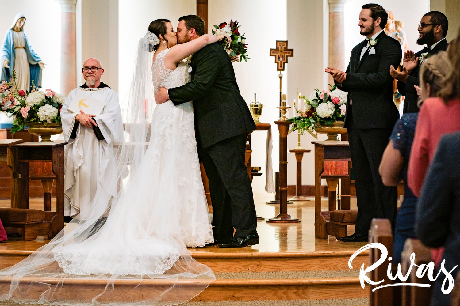 A candid picture of a bride and groom sharing a kiss at the end of their wedding ceremony in Lawrence, Kansas. 