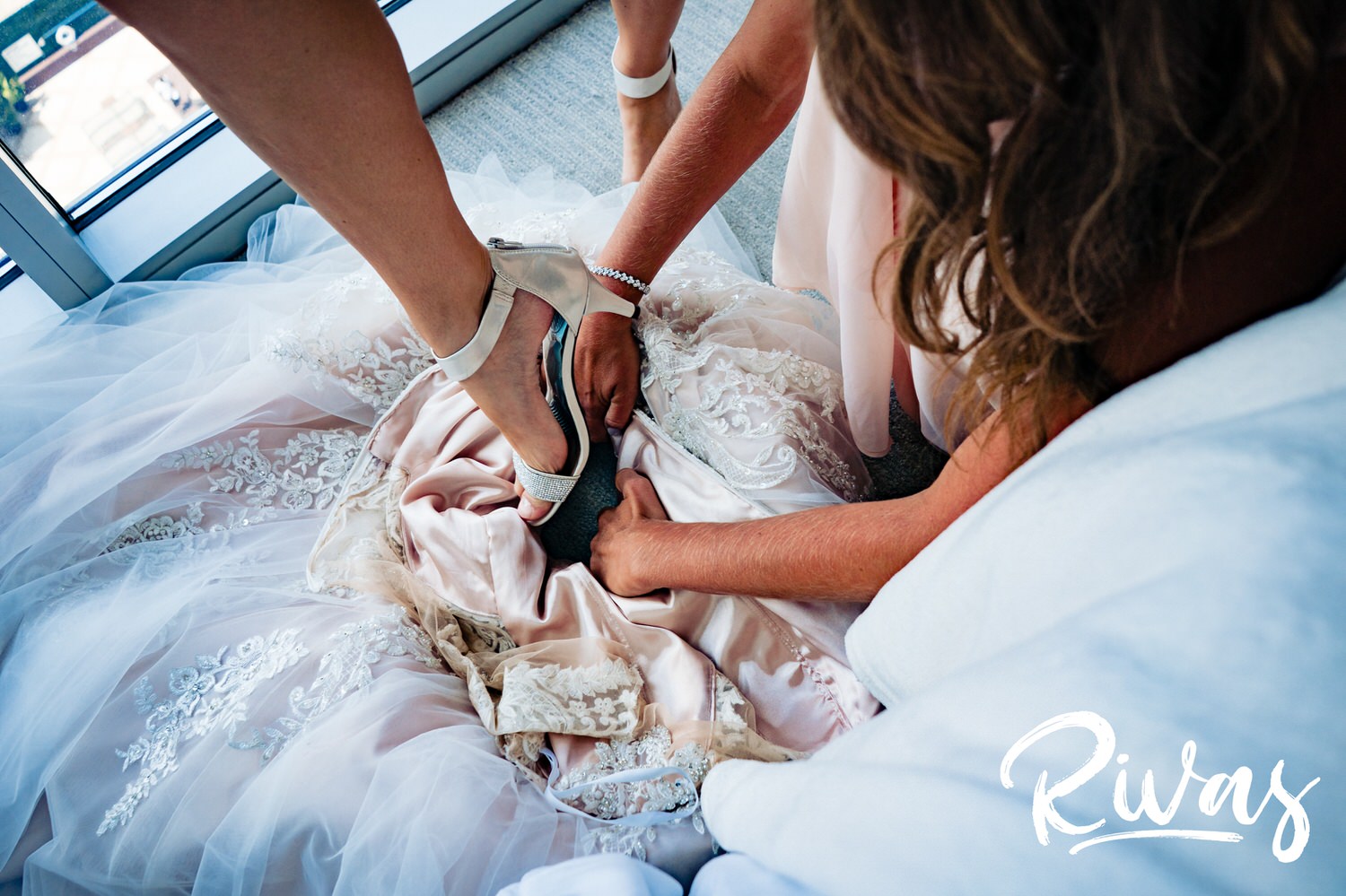 A candid picture taken from above of a bride in her bejeweled shoes stepping into her wedding gown on the morning of her wedding day in Kansas City. 