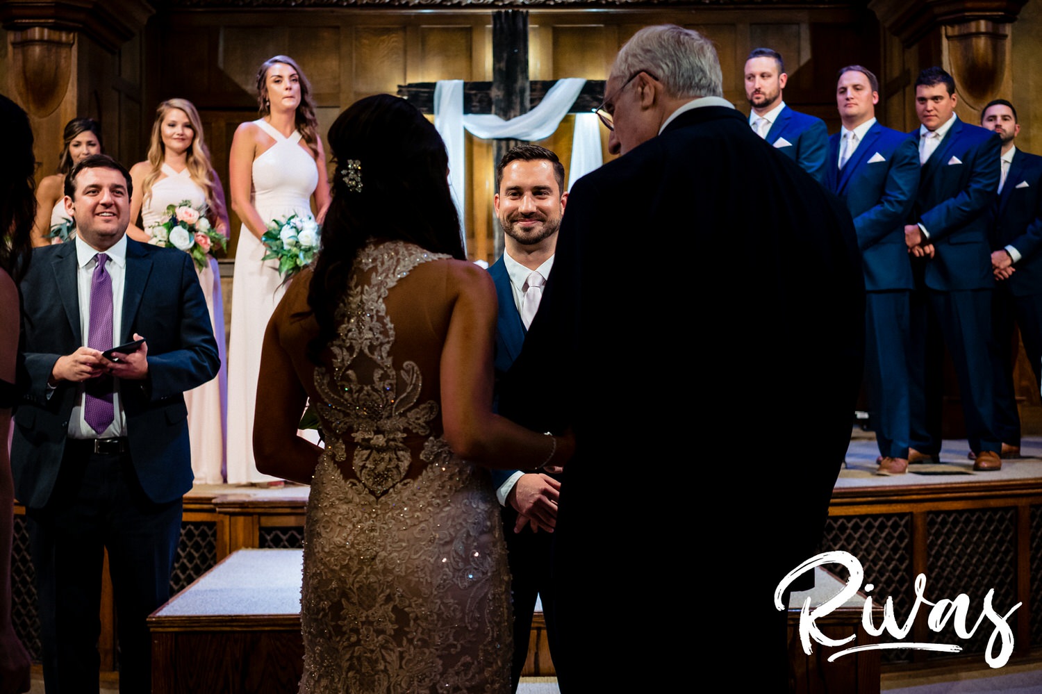 A candid picture, taken from behind the bride and her grandpa, as they stand at the front of the church facing her groom, just before her grandpa gives her away. 