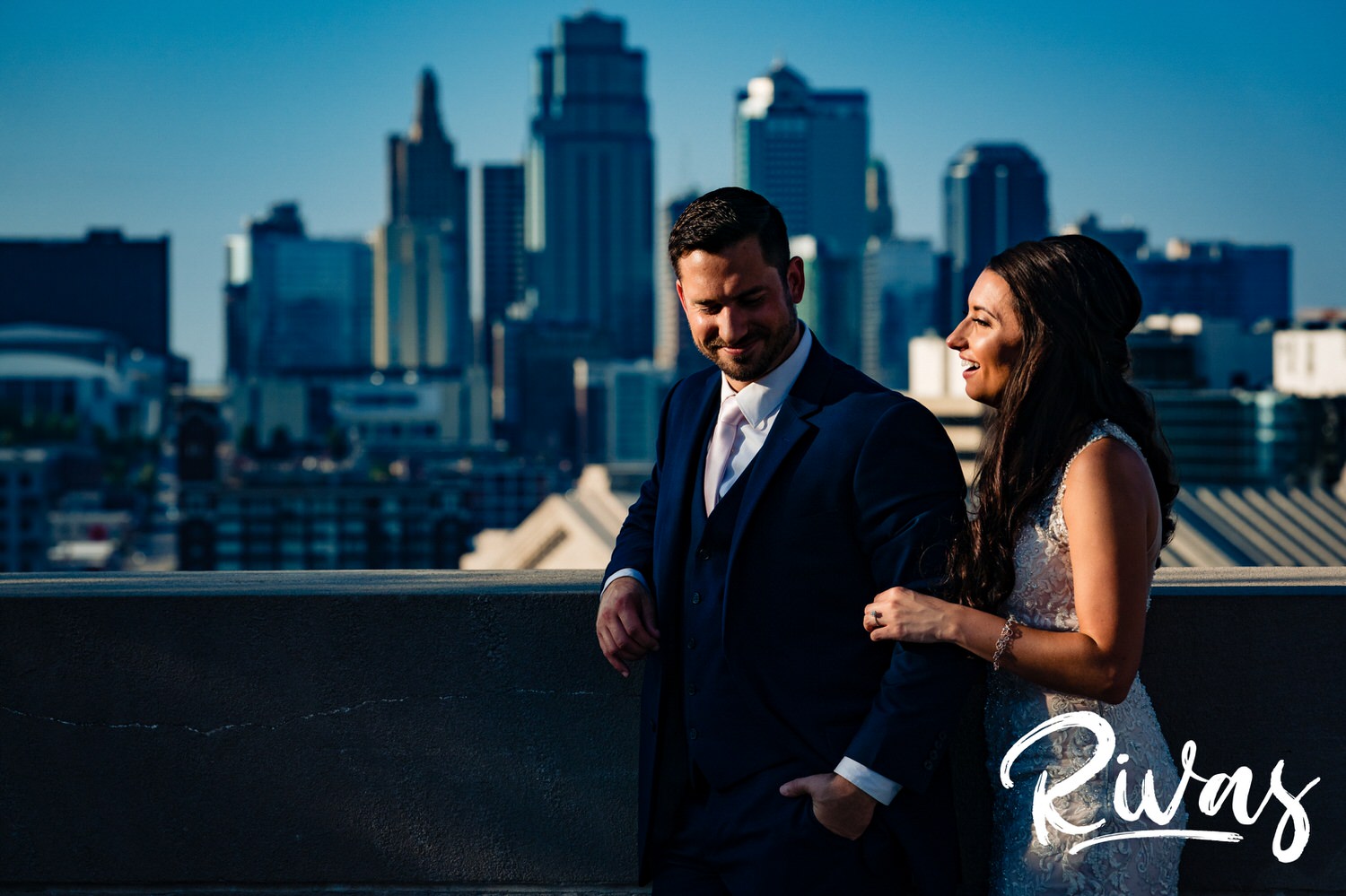 A bold, dramatic, colorful portrait of a bride and groom laughing together as they stand in front of the Kansas City Skyline at Liberty Memorial on their wedding day in Kansas City. 