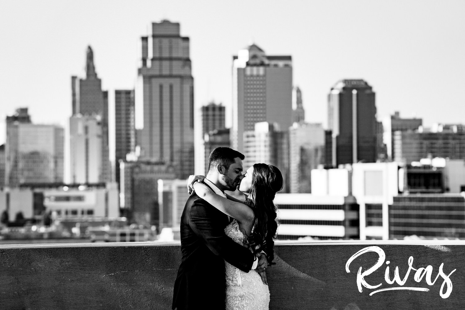 A bold, dramatic, black and white portrait of a bride and groom laughing together as they stand in front of the Kansas City Skyline at Liberty Memorial on their wedding day in Kansas City. 