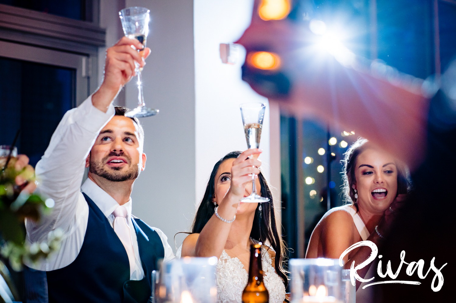 A candid, close-up picture of a bride and groom raising their champagne flutes in a toast during their wedding reception at The Gallery in downtown Kansas City on their wedding day. 