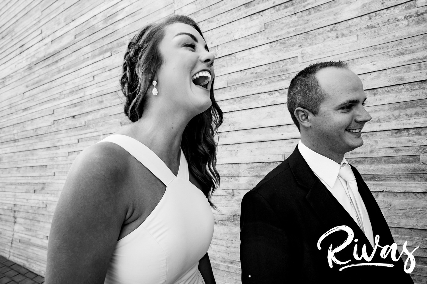 A candid black and white picture of a bridesmaid and groomsman laughing on a Kansas City wedding day. 