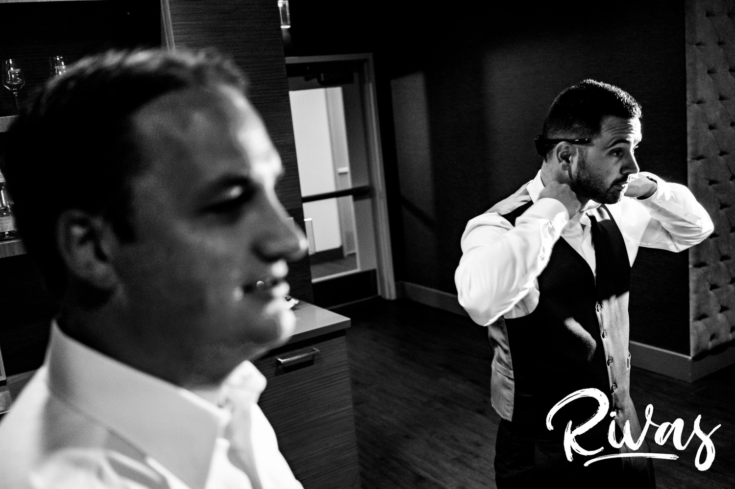 A candid black and white picture of two groomsmen getting dressed on a wedding morning in downtown Kansas City. 