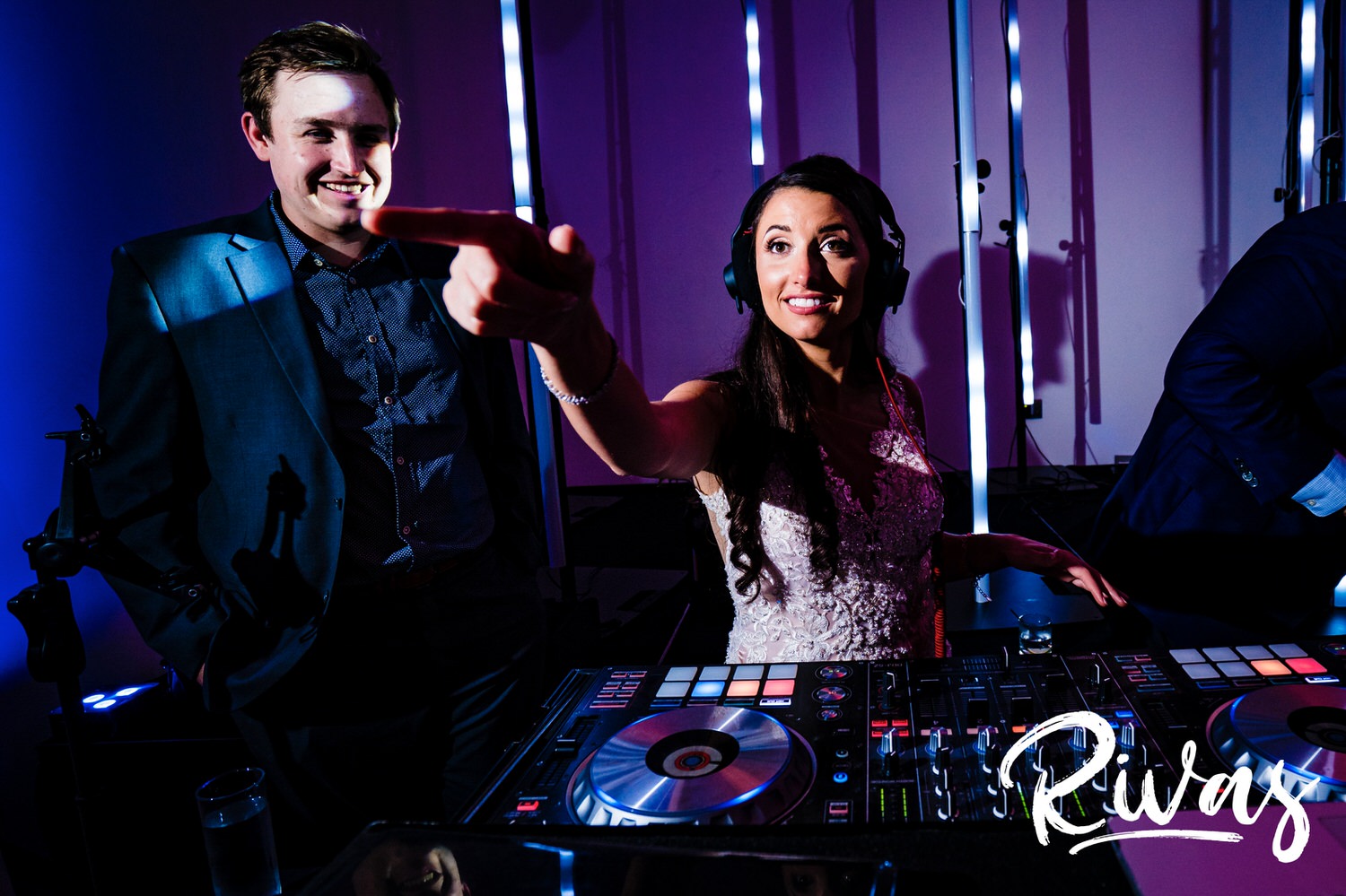 A candid picture of a bride behind the DJ booth with her arms raised in the air as she djs her own wedding reception at The Gallery Event Space in downtown Kansas City. 