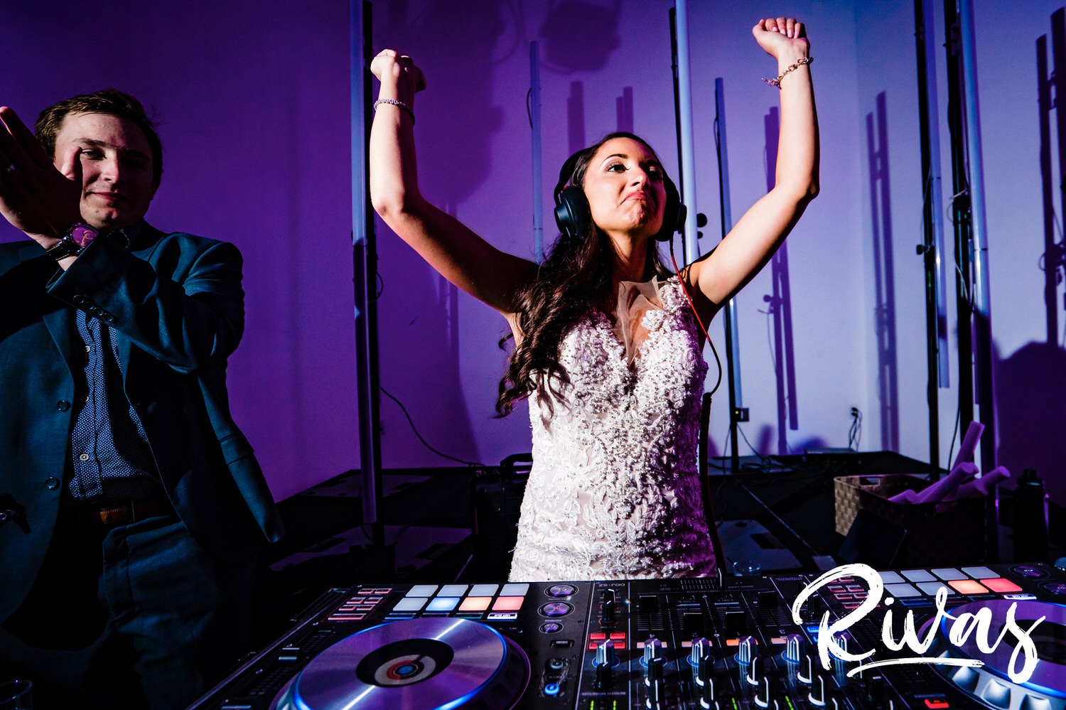 A candid picture of a bride behind the DJ booth with her arms raised in the air as she djs her own wedding reception at The Gallery Event Space in downtown Kansas City. 