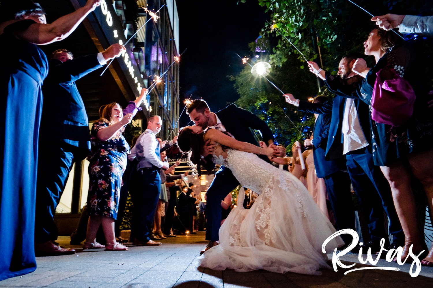 A candid picture of a bride and groom exiting their wedding reception at The Gallery Event Space under an arc of sparklers on the night of their wedding in downtown Kansas City. 
