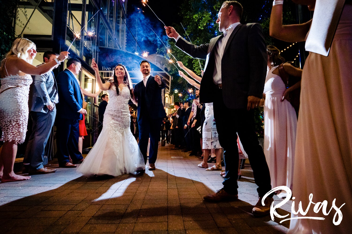 A candid picture of a bride and groom exiting their wedding reception at The Gallery Event Space under an arc of sparklers on the night of their wedding in downtown Kansas City. 