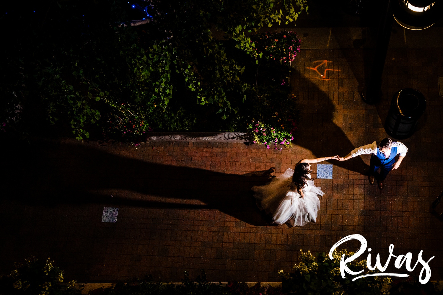 A candid picture taken from the balcony of The Gallery Event Space, looking down at the sidewalk, as a bride and groom slowly dance and twirl on the night of their wedding in downtown Kanas City. 