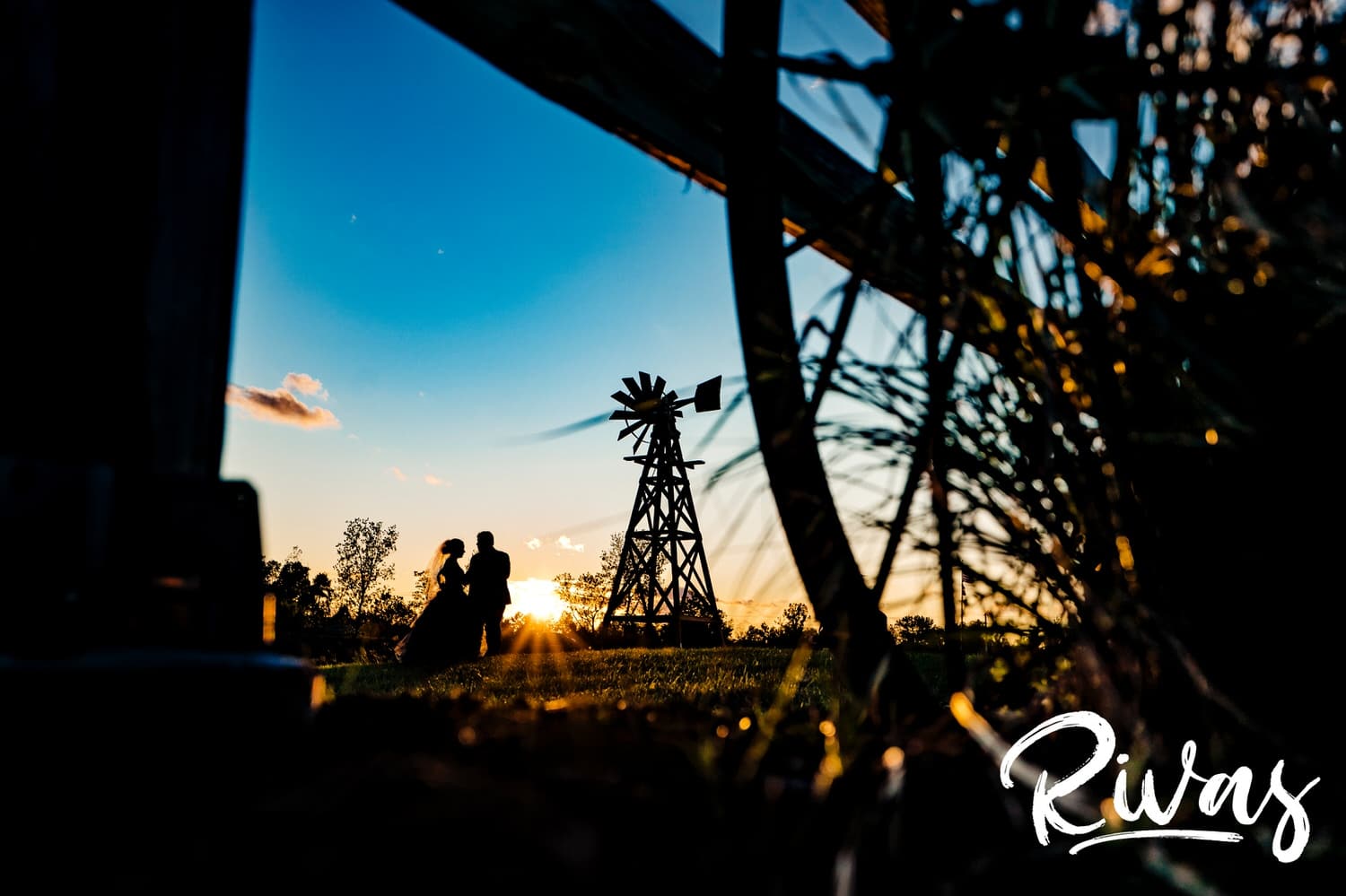 A dramatic silhouettte of a bride and groom standing underneath a windmill outside Piazza Messina on their wedding day. 