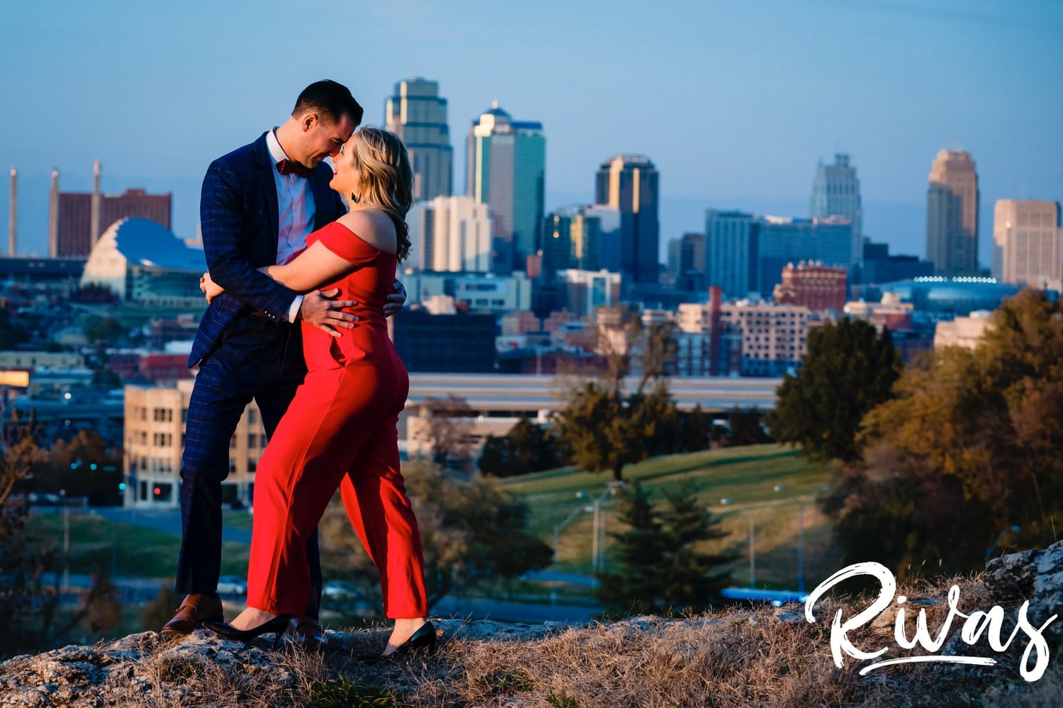 A bright, candid picture of an engaged couple leaning in to share an embrace during their engagement session at The Scout in Kansas City. 