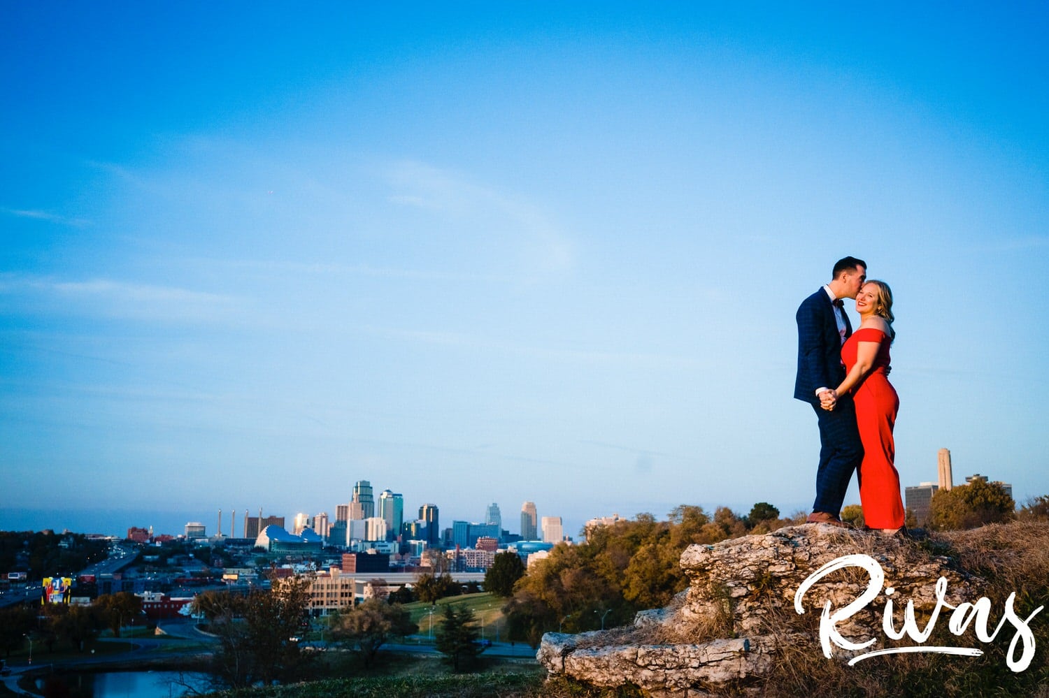 A bright, candid picture of an engaged couple leaning in to share an embrace during their engagement session at The Scout in Kansas City. 