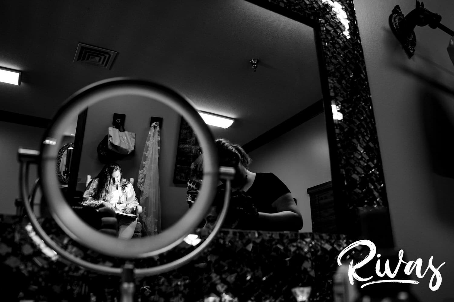 A candid black and white picture of two mirrors, one showing the reflection of a bride writing her vows on the morning of her Fire Stables wedding. 