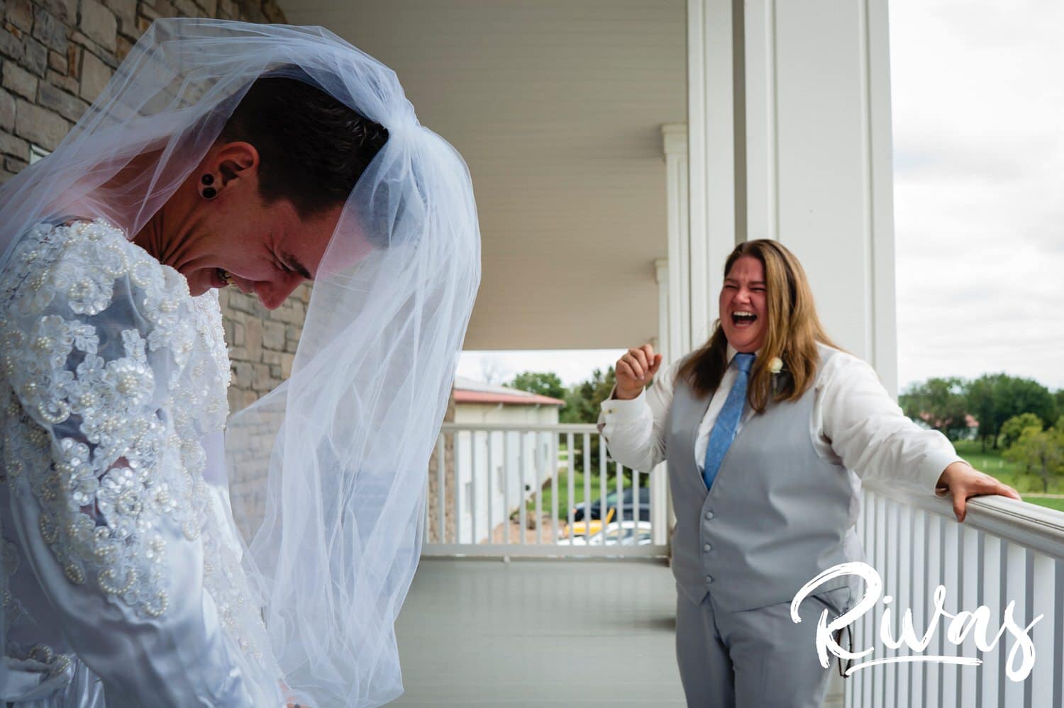 A candid picture of a woman reacting to seeing her brother in a 1980s wedding dress and veil on the morning of her wedding at Fire Stables. 