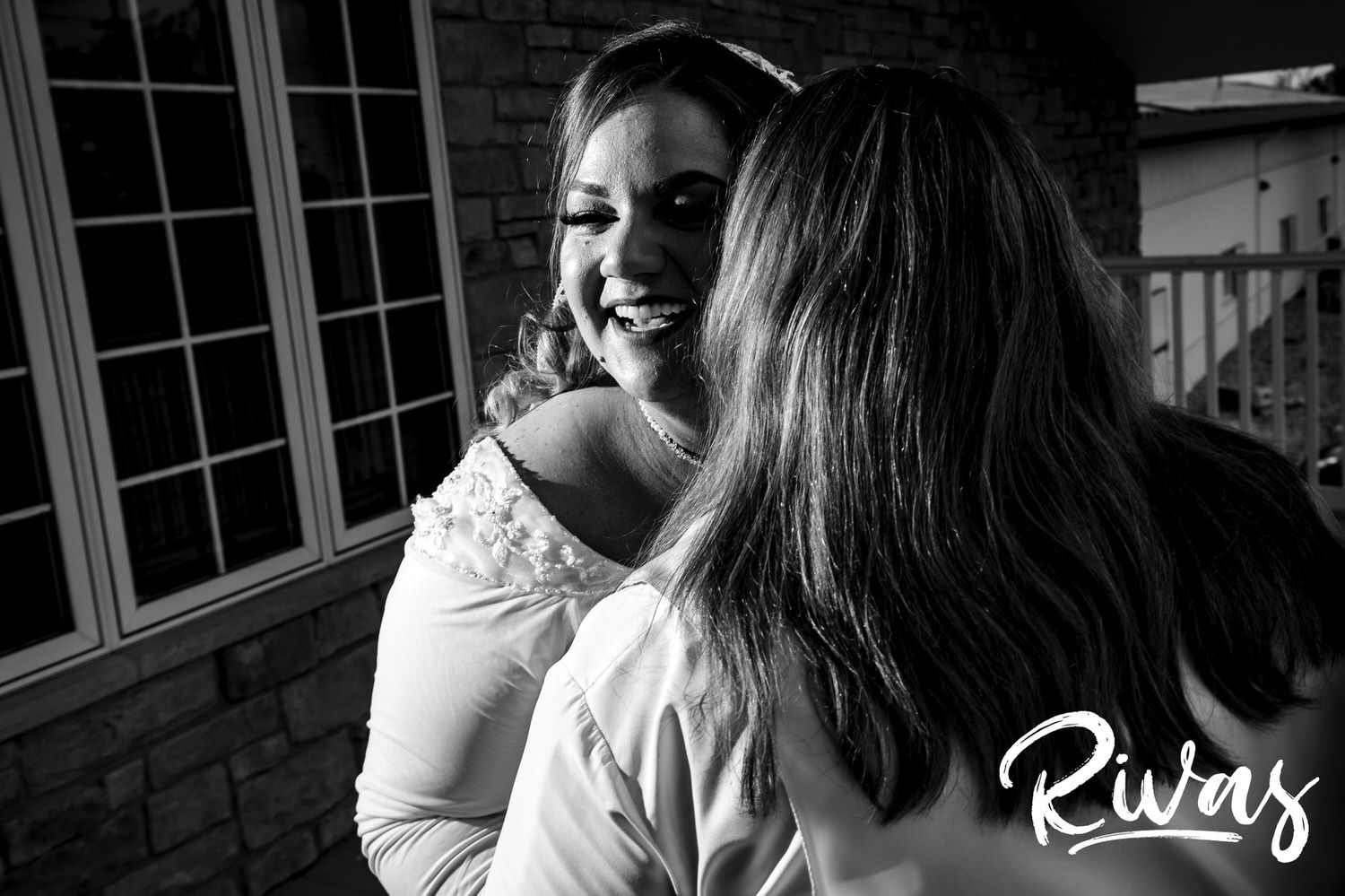 A candid black and white picture of two brides sharing a loving embrace just after their first look at Fire Stables on their wedding day. 