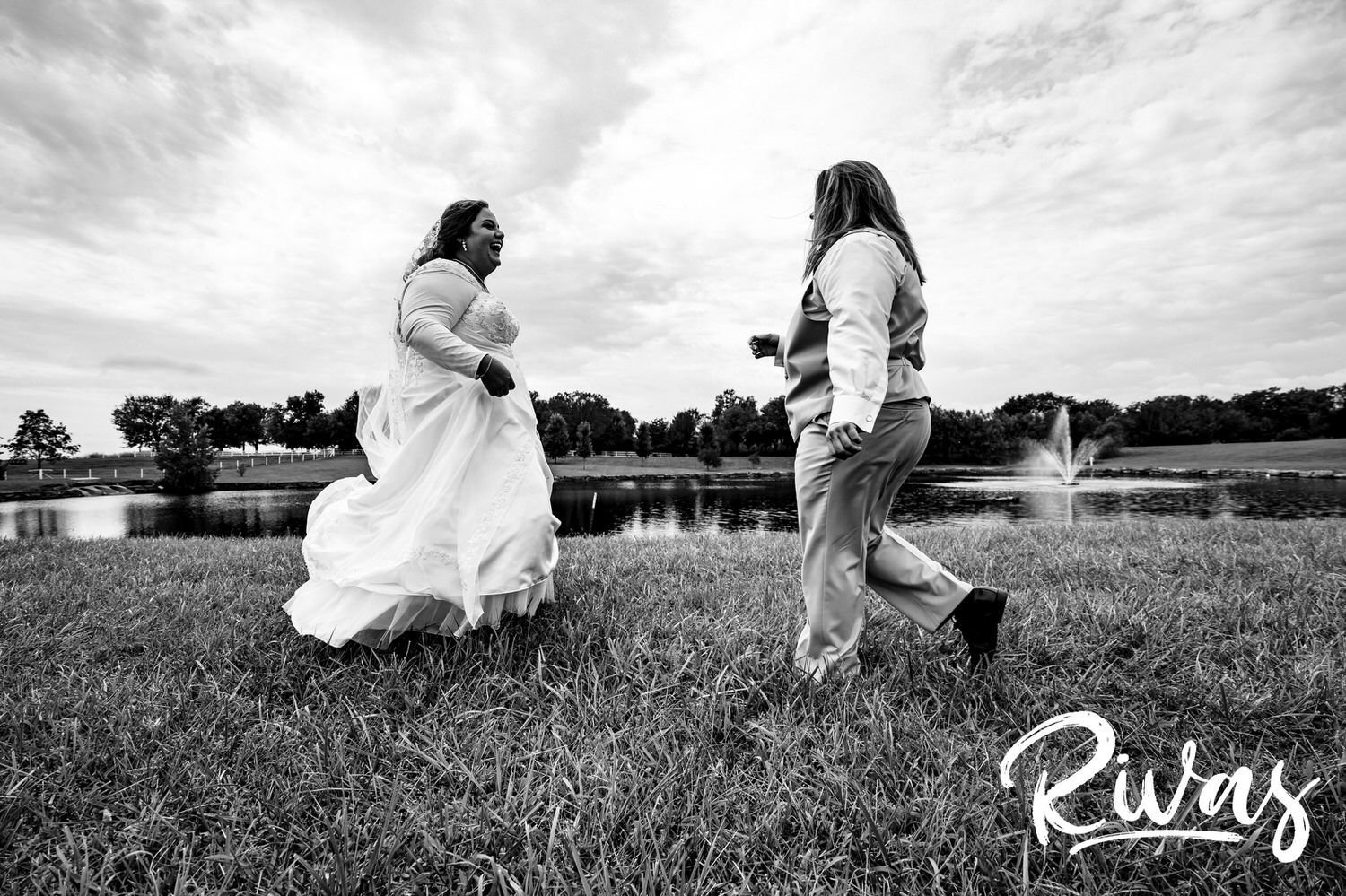A candid, black and white picture of two brides running towards each other in celebration on their wedding day at Fire Stables. 
