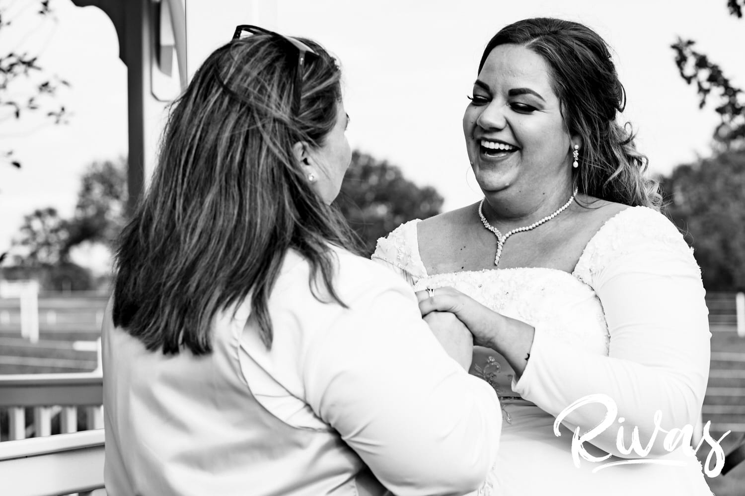An intimate black and white picture of two brides laughing together on their wedding day at Fire Stables. 