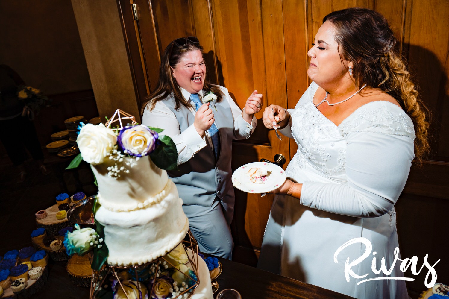 A candid, colorful picture of a bride laughing hysterically just after she's fed her wife a bit of wedding cake covered in Crisco during their wedding reception at Fire Stables. 