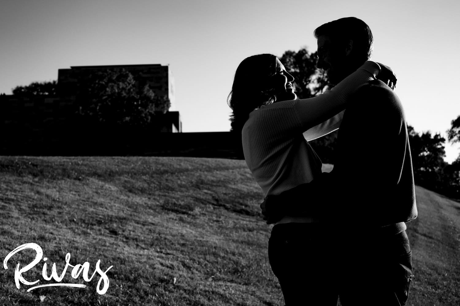 A candid black and white photo of an engaged couple sharing an embrace and laughing together during their engagement session at Liberty Memorial in Kansas City. 