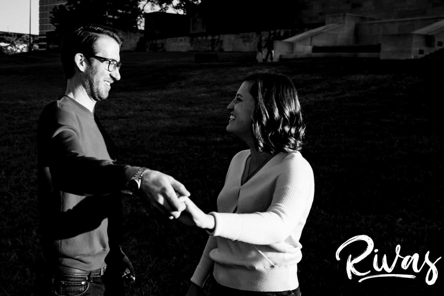 A candid black and white photo of an engaged couple sharing an embrace and laughing together during their engagement session at Liberty Memorial in Kansas City. 