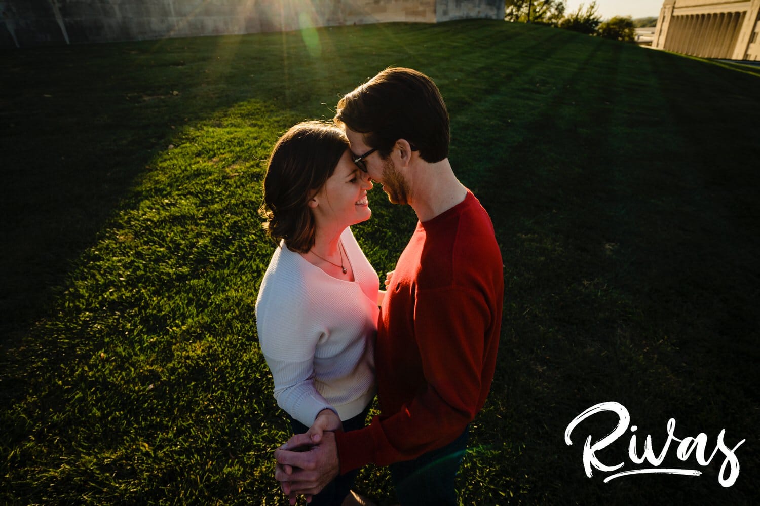 An intimate, colorful picture of an engaged couple standing together, holding hands and smiling gently at each other during their engagement session at Liberty Memorial in Kansas City. 