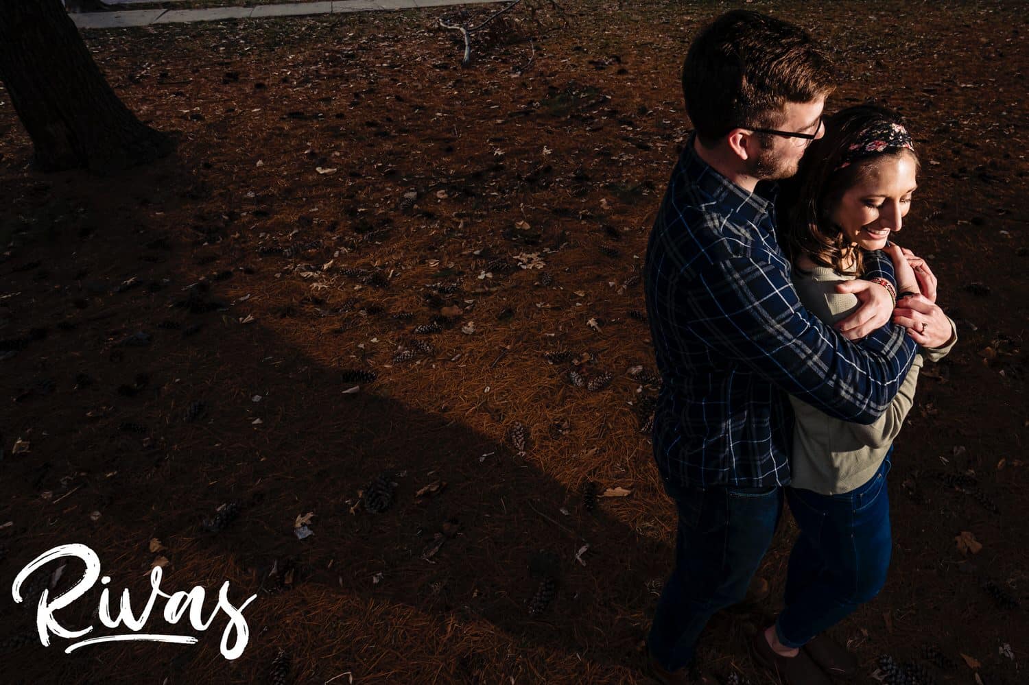 A bold portrait of an engaged couple standing in a field of fallen pine needles during their winter engagement session. 