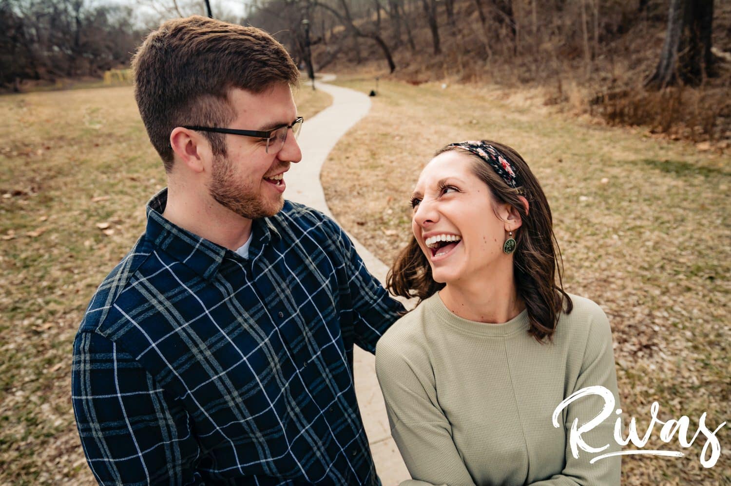 A tight, candid picture of an engaged couple sharing a laugh and an embrace during their winter engagement session. 
