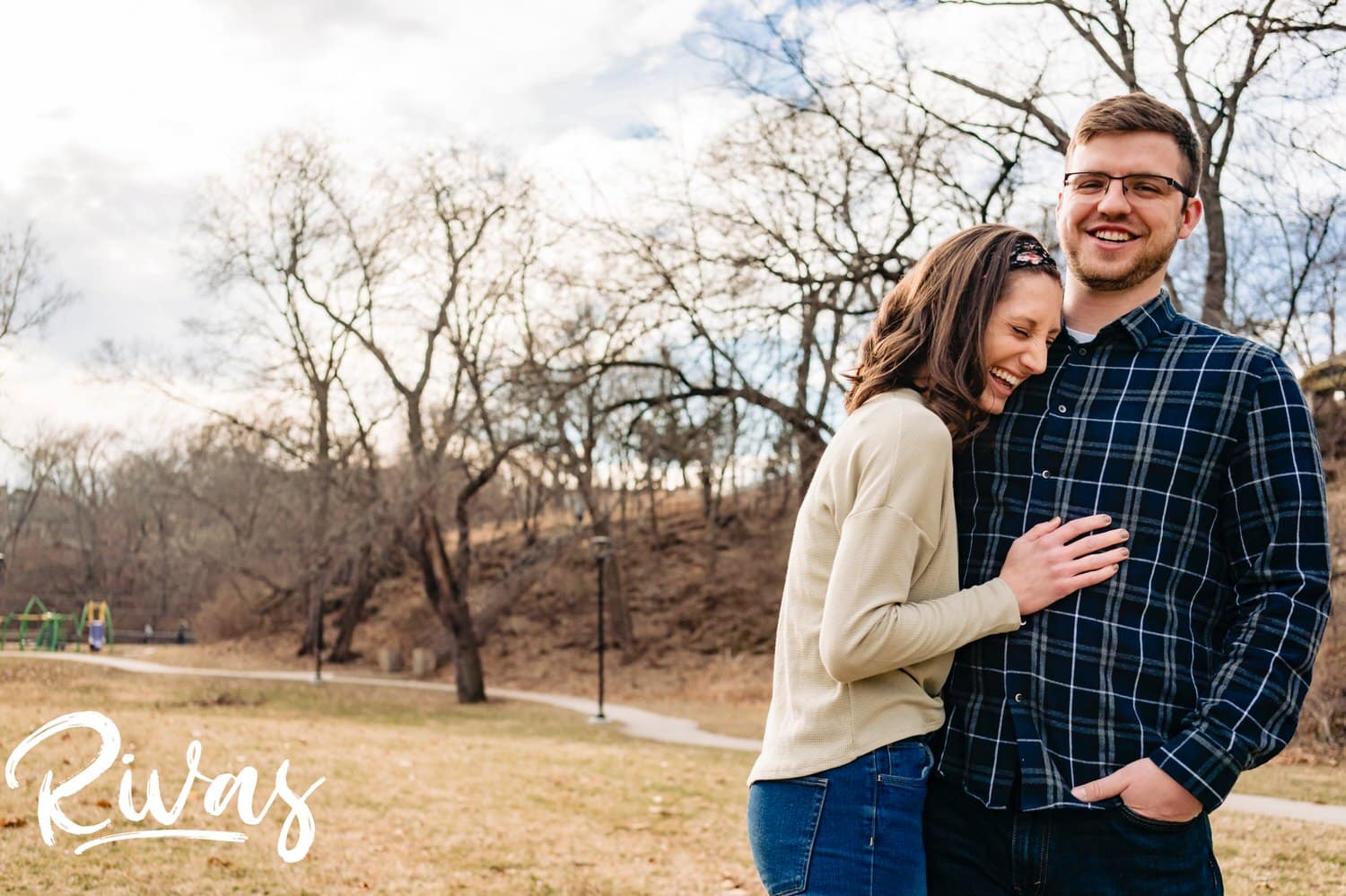 A tight, candid picture of an engaged couple laughing and sharing an embrace during their winter engagement session in Kansas City. 