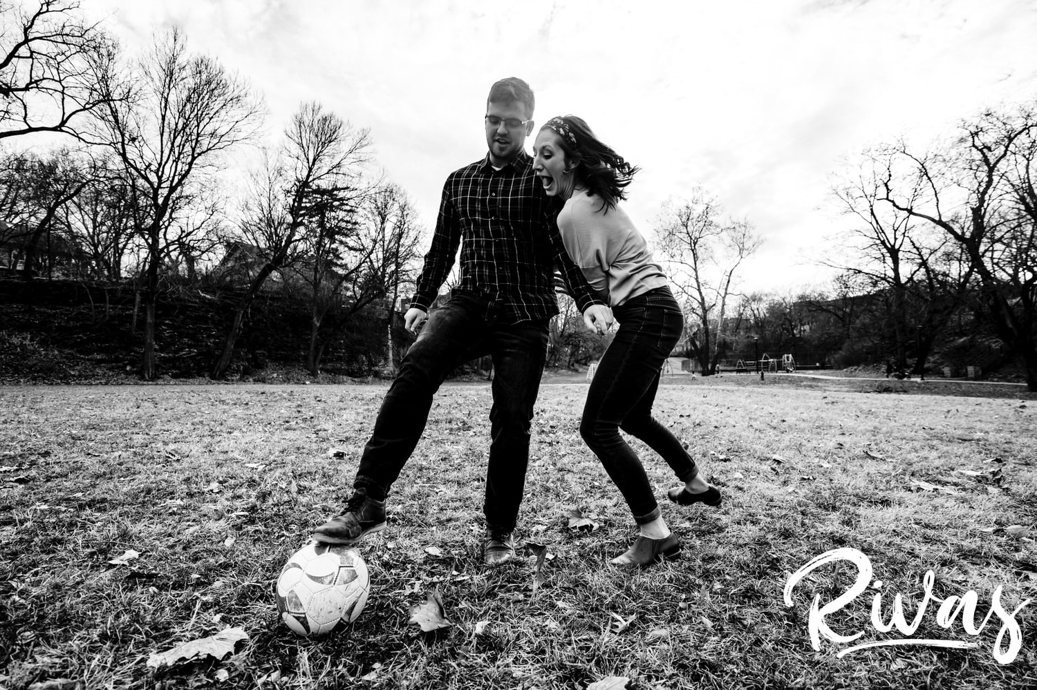 A candid black and white picture of an engaged couple playing soccer together during their engagement session in Kansas City. 