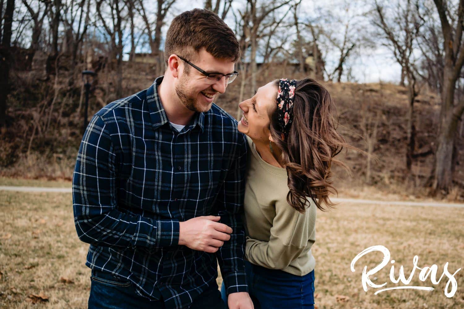 A colorful, candid picture of an engaged couple sharing an embrace and laughing together during their winter engagement session in Kansas City. 